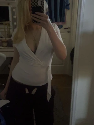 Vit omlottopp - Vit omlotttopp i mjukt material. V-ringad med knyt i sidan som ger en smickrande passform. Använd fåtal gånger och i fint skick.