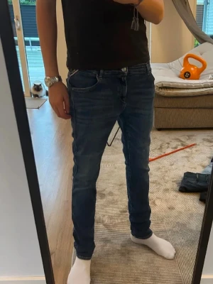 Mörkblå slim fit jeans - Säljer ett par mörkblå slim fit jeans med klassisk femficksdesign och snygga slitningar. Jeansen har normal midja och smal passform hela vägen ner. Materialet är mjukt denim med lite stretch för extra komfort. Perfekta till vardagslooken!