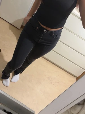 Svarta raka jeans med hög midja - Säljer ett par svarta jeans med rak passform och hög midja. Jeansen har klassisk femficksdesign och stängs med knapp och dragkedja. Materialet är denim med lite stretch för skön passform. Perfekta till en enkel topp eller hoodie.