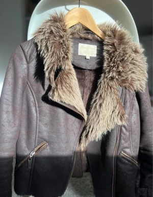 Jacka - Brun jacka med dragkedja och detaljer. Jackan har en krage i fuskpäls.  Nytt skick   Passar för storlek Xs-M  Kan skicka mer bilder vid behov