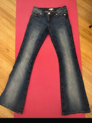 Bootcut jeans från Gina Tricot - Mörkblå bootcut jeans från Gina Tricot med snygga slitningar och kontrastsömmar. Klassisk femficksmodell med låg midja och utsvängda ben. Perfekta för en avslappnad och trendig look. Lite slitage längs nere på ena benet😊💞hör av er vid frågor