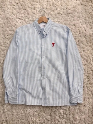 Ami Paris skjorta - Säljer denna sjukt snygga skjortan från Ami Paris. Skjortan är i sjukt bra skick, använd vid få tillfällen. Den minsta defekten syns på bild tre. Hör av er vid eventuella frågor eller funderingar!   