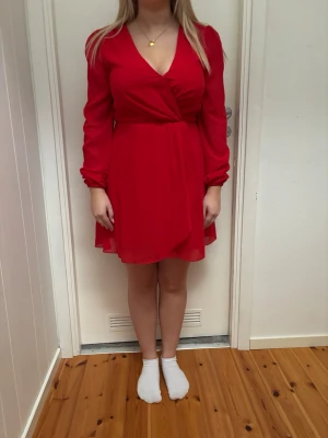 Röd omlottklänning med långa ärmar - Snygg röd omlottklänning med v-ringning och långa ärmar. nästan aldrig använd. STOLEK 38💗