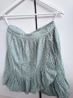 Grön prickig volangkjol - Söt kortkjol i ljusgrönt med vita prickar och volangdetalj längs nederkanten. Sträcker sig till lite ovanför knäna på mig (173). Perfekt till våren och sommaren. Säljer då den inte kommer till användning längre💕