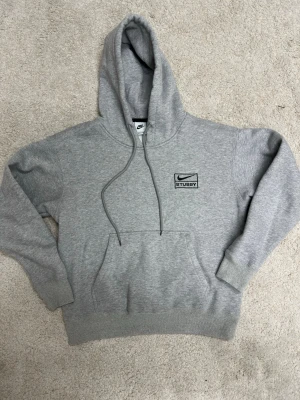 Nike Stussy Hoodie Grå (S) - Grå Nike Stussy hoodie i storlek S kvalitet mycket bra förutom ett hål som enkelt går att sy ihop. Priset går även att diskuteras✌️