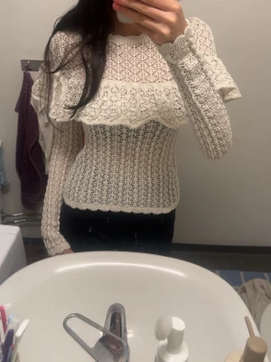Vit virkad stickad tröja med volang - Säljer en söt vit stickad tröja med virkat mönster och volangdetalj över bröstet och axlarna. Tröjan passar till allt och har använts typ 2 gånger. Priset kan sänkas 
