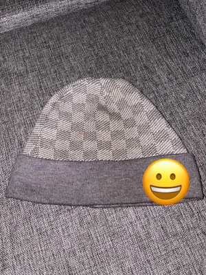 Gråmelerad mössa med rutmönster - Snygg gråmelerad mössa med klassiskt rutmönster och bred uppvikt kant. Perfekt accessoar för att hålla värmen och ge en stilren touch till din outfit. Mjuk och bekväm passform.