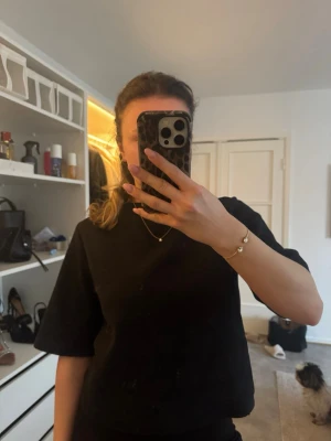 Svart boxy t-shirt med vida ärmar - En svart t-shirt med boxy passform och vida, lite längre ärmar. T-shirten har rund halsringning och har ett lite tjockare material. Perfekt för en clean och stilren look.