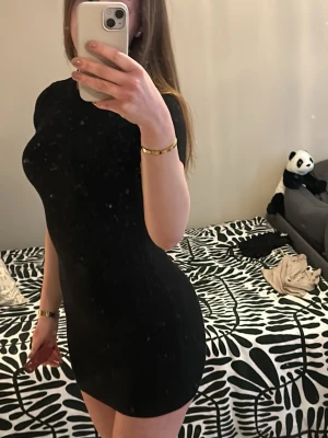 Svart ribbad kortklänning i stickad material Gina Tricot - Snygg svart ribbad kortklänning med tight passform och korta ärmar. Perfekt för dig som gillar en enkel men stilren look. Klänningen är stretchig och sitter riktigt bra på kroppen. Passar dig som vill ha en klassisk och trendig outfit. Materialet är lite varmare och går att använda på vintern med strumpbyxor