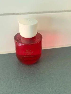 Zara Red Vanilla Candy parfym - Zara Red Vanilla Candy parfym från Candy Collection. Flaskan är rund och genomskinlig i röd färg med vit kork. Doften har en söt och fruktig karaktär, perfekt för dig som gillar vaniljtoner. Snygg och modern design som sticker ut på hyllan.