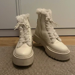 Offwhite beige boots med fuskpäls - Snygga vita stövletter från Steve Madden med 5cm platåsula och fuskpäls längs kanten och plösen. Dragkedja på sidan och snörning framtill. Perfekta för att lyfta din vinterstil med en trendig touch. Ord pris 1800kr