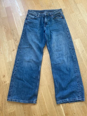 Blå wide jeans från Weekday - Säljer ett par blåa wide leg jeans från Weekday, modell Mino Low Wide. Klassisk femficksdesign och raka, vida ben. Perfekta för en avslappnad och trendig look. Tillverkade i bomull för skön känsla.