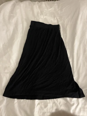 Svart långkjol i mjukt tyg - En enkel och stilren svart långkjol med lätt utställd passform. Kjolen ör väldigt stretchig 