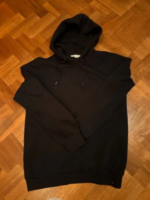 Svart basic hoodie från pier one  - En stilren svart hoodie med huva och dragsnören. Klassisk passform med ribbade muddar vid ärmslut och nederkant. Perfekt för en avslappnad look och enkel att matcha med andra plagg. Tillverkad i mjukt material för extra komfort. Storlek S men skulle mer säga att den passar M! Skriv vid funderingar! 