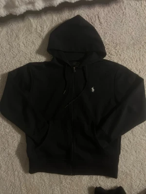 Ralph Lauren Zip - Klassisk svart zip-hoodie från Ralph Lauren. Finns 2 stycken i storlek S. Passar perfekt till vardag och skola.