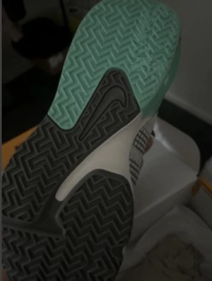 Nike sneakers med rutigt mönster - Säljer ett par Nike sneakers med rutigt mönster i grått och vitt. Skorna har en unik sula i svart och mintgrönt, samt klassiska snörningar. Ovandelen är i textilmaterial och designen är modern och sportig. Perfekta för dig som vill sticka ut med din stil.