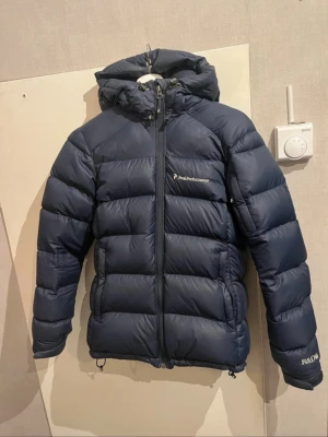 Mörkblå dunjacka från Peak Performance - Peak performance jacka i storlek S säljer då den inte kommer till användning. Den har en reva på ena armen (se sista bilden) super lätt att laga, köpt för 1200kr säljer för 800kr