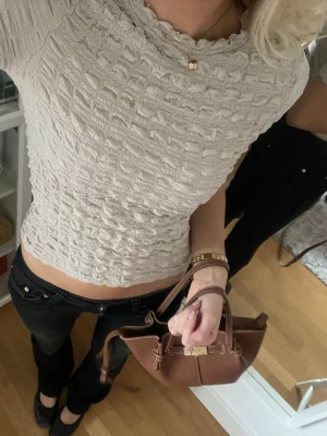 Beige croppad topp med struktur - Säljer en beige croppad topp med coolt strukturerat tyg och rund halsringning. Toppen har korta ärmar och sitter snyggt med en normal passform. Perfekt att styla med jeans eller kjol för en trendig look.
