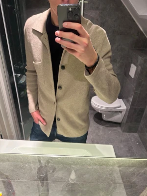 Beige kofta med fickor  - Säljer en riktigt schysst stickad kavaj-liknande tröja som passar perfekt nu till våren. Tröjan är i riktigt bra skick och skönt material. Jag på bilden är 188cm och bör storlek M. Hör av er vid frågor och eventuella prisförslag:)