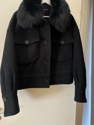 Svart pälsjacka från Meotine -  Svart pälsjacka från Meotine med fluffig pälskrage och stora bröstfickor med knappar. Jackan har en boxig passform, markerade muddar och knäppning framtill. Storlek M/L. Den är i använt skick och är därav lite sliten, främst i ärmmuddarna vilket syns på sista två bilderna. Skriv gärna vid funderingar eller för fler bilder!💕☺️