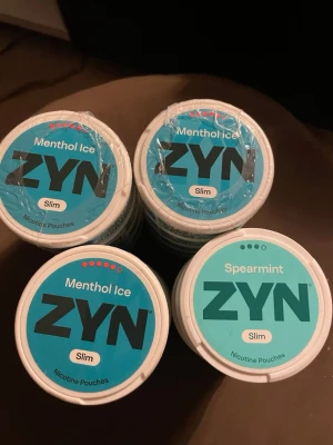 ZYN Slim Menthol Ice & Spearmint - Flera dosor ZYN Slim nikotinpåsar i smakerna Menthol Ice och Spearmint. Dosorna är vita med blå och turkosa lock och tydlig märkning av smak och variant. Perfekt för dig som gillar fräscha smaker och slim-format,10 för 300 