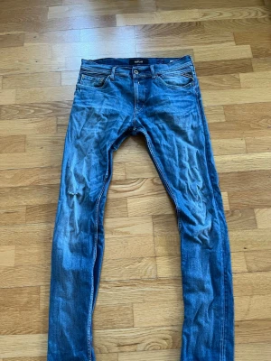 Blå slim fit jeans från Replay - Waist:33.                                                             Length:32.                                                         Snygga blå slim fit jeans från Replay med klassisk femficksdesign. Jeansen har en något tvättad look och smal passform som ger en modern stil. Perfekta för dig som gillar en avslappnad men trendig vibe.