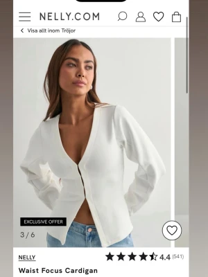 Vit cardigan med djup v-ringning - Stilren vit cardigan från Nelly med djup v-ringning och knappstängning framtill. Tröjan har långa ärmar och en figurnära passform som framhäver midjan. Perfekt att matcha med jeans för en trendig look. Har bara provat och tagit bort lapp helt ny