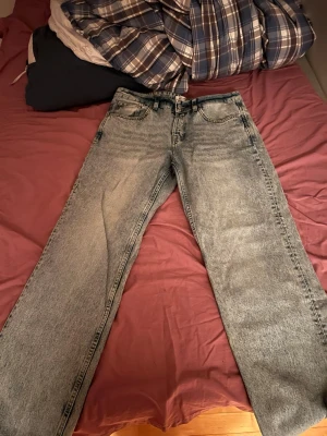 Baggy jeans - Säljer ett par ljusblå jeans från Only & Sons med rak passform och klassisk femficksdesign. Jeansen har en tvättad look och stängs med knappgylf. Perfekta för en avslappnad och trendig stil.