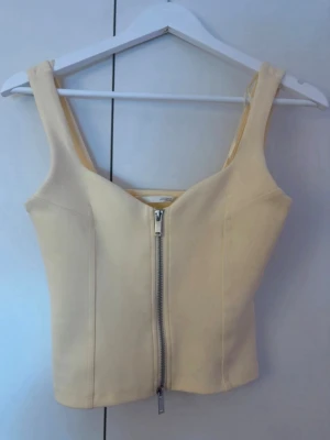Ljusgul topp från Zara - Trendig ljusgul topp från Zara med breda axelband och en snygg dragkedja framtill. 