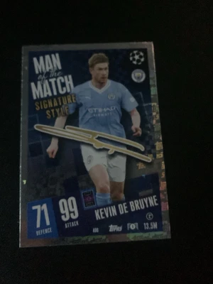 Match Attax Man of the Match kort - Säljer ett Match Attax Man of the Match Signature Style samlarkort från Topps med Manchester City-tema. Kortet har blå och vita färger, holografiska detaljer och visar en spelare i Manchester Citys matchställ. Perfekt för samlare av fotbollskort.