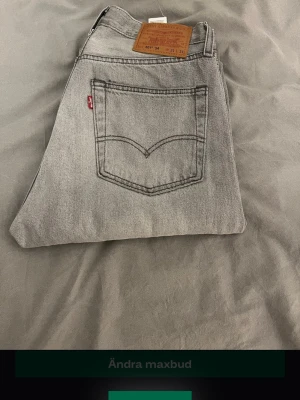 Grå Levi's 501 jeans - Säljer ett par grå Levi's 501 jeans med klassisk rak passform och femficksmodell. Jeansen har den ikoniska läderpatchen bak i midjan och tydliga sömmar på bakfickorna. Tillverkade i slitstark denim med vintage vibe.