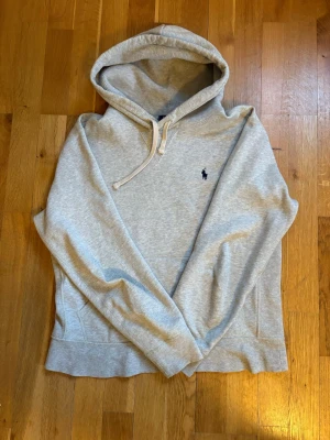 Grå hoodie från Polo Ralph Lauren - Snygg ljusgrå hoodie från Polo Ralph Lauren med klassisk huva. Broderad logga i mörkblått på bröstet. Mjuk bomullsblandning och skön insida. Perfekt för en chill och stilren look. Model 188, 70kg.     Pris kan diskuteras!!!