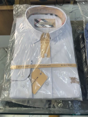 Vit skjorta från Burberry - Klassisk vit skjorta från Burberry med knappar framtill och broderad logga på bröstet. Skjortan har en stilren design och är tillverkad i bomull. Perfekt för dig som gillar en clean och tidlös look.