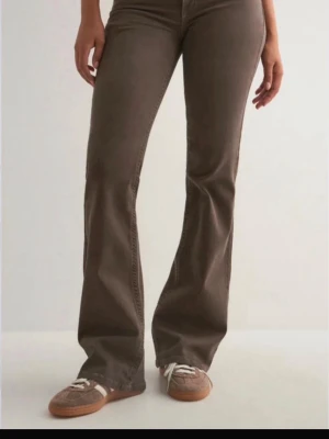 Bruna bootcut jeans från nelly  - Snygga bruna bootcut jeans från nelly  med klassisk femficksdesign och dekorativ söm på bakfickan. Jeansen har normal midja och är tillverkade i ett stretchigt denimtyg som sitter bekvämt. Perfekta för en avslappnad och trendig look.