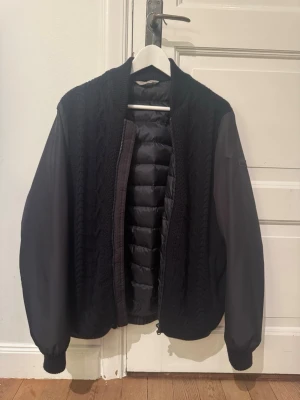 Mörkblå stickad cardiganjacka - Snygg mörkblå cardiganjacka från falconeri med stickad framsida och quiltad insida. Ärmarna är i ett slätt material som kontrasterar mot den stickade delen. Dragkedja framtill och ribbade muddar vid ärmslut. Nypris ligger runt 4500 och är använd ett fåtal gånger och är perfekt för vår/höst. Storleken är large men fungerar också perfekt för medium. Om ni har frågor eller annat är det bara att skriva!