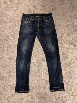 Nudie Thinn Finn - Ett par schyssta nudie thinn finn i storlek 30/30 med sköna slitningar och snygg tvätt. Jeansen har en lagning vid skrevet.  Skicka gärna frågor samt bud.