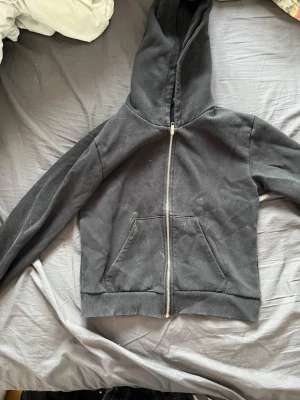 Svart hoodie med dragkedja 157 - Svart hoodie från 157 med dragkedja framtill och två fickor. Klassisk modell med huva och ribbade muddar vid ärmslut och nederkant. Perfekt för en avslappnad stil. Tillverkad i mjukt bomullsmaterial.