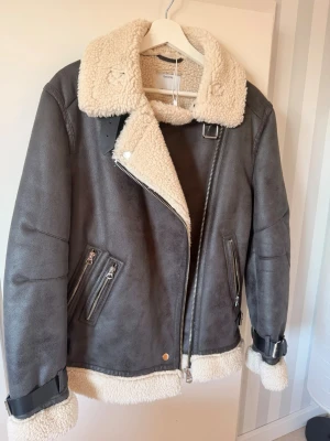 Grå pälsjacka med fuskpälsdetaljer - Snygg grå pälsjacka från Bershka jackan är oanvänd passar dig som har S eller M 