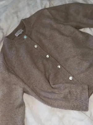 Beige kofta other stories - Superfin beige kofta från & Other Stories i mjuk ullmix. Koftan har halvlånga ärmar, rund halsringning och snygga knappar framtill. 