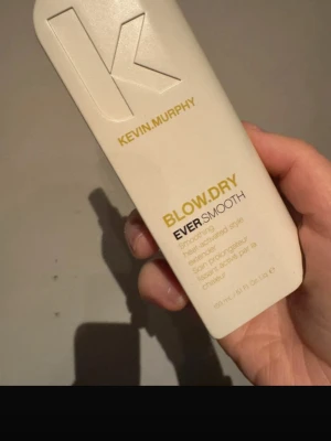 Kevin Murphy Blow.Dry Ever.Smooth - Säljer en Kevin Murphy Blow.Dry Ever.Smooth, en värmeaktiverad stylingprodukt som ger ett slätt och mjukt resultat. Kommer i en vit plastflaska med guld- och svart text. Perfekt för dig som vill ha ett långvarigt, frissfritt hår.