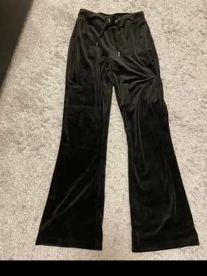 Superfina velourbyxor från Gina Tricot - Svarta velourbyxor i mjukt och lyxigt material som ger en snygg glow-look. Trendig bootcut/flare-modell som sitter smickrande på benen. Bekväm resårmidja med snörning – både snyggt och skönt.  Har aldrig använt de så de är i mycket fint skick, inga fläckar eller defekter. Perfekta till både vardag, skola och mysiga outfits – kan stylas upp med topp och jacka eller ner med hoodie.  🖤 Stilrena 🖤 Bekväma 🖤 Trendiga 🖤 Lätta att matcha  Redo för ny ägare ✨