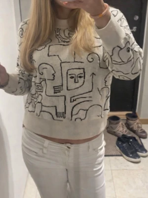 Beige stickad tröja med grafiskt mönster - Säljer en beige stickad tröja med svart grafiskt mönster ifrån monki. Använd en gång! Sjukt cool tröja!🩷🤍