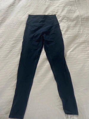 Lululemon tights - Säljer ett par marinblå high waist leggings från Lululemon. De har en tight passform och är tillverkade i ett stretchigt, mjukt material som sitter skönt mot kroppen. Perfekta för träning eller chill dagar. Klassisk och stilren design utan synliga fickor. Storlek 4 är som XS/S. Aldrig använda nypris ligger på 1100