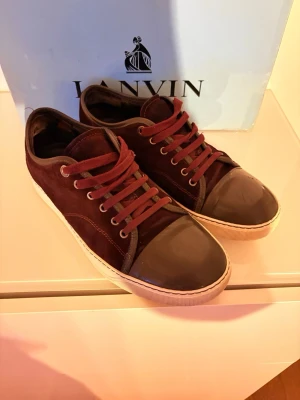 Lanvin skor - Snygga vinröda sneakers från Lanvin med ovandel i mocka och tåparti i blankt läder. Skorna har matchande vinröda skosnören, vita sulor och metallfärgade öljetter. Perfekt för dig som gillar stilrena och exklusiva sneakers med en unik touch. Nypris:4500kr | Mitt pris:1650 | Skick: 8/10 | Priset går såklart att diskutera om men inga deffekter som man känner med skorn på eller som man ser!😃🙌
