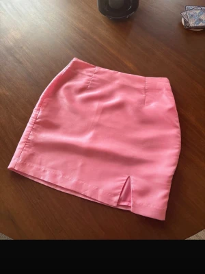 Kjol - Jättefin rosa kortkjol med liten slits framtill. Kjolen har en enkel och stilren design som passar perfekt till både vardags och mer uppklädda tillfällen. Den är från Hanna Schönbergs kollektion med NAKD och är i mycket fint skick. Tyvärr för liten för mig och glömde att skickas tillbaka så den är som ny🩷🩷🩷