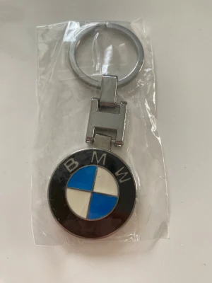 BMW nyckelring - Snygg nyckelring i metall med BMW:s klassiska logotyp i svart, blått och vitt. Rund form med tydlig BMW-text och emaljerad yta. Perfekt accessoar för dig som gillar bilar och vill ha något stilrent till nycklarna.