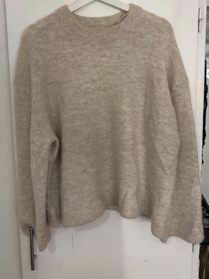 Beige oversized stickad tröja - Mysig beige stickad tröja i oversized modell med rund halsringning och ribbade muddar vid ärmslut och nederkant. Perfekt för lager på lager och enkel att matcha till olika outfits. Materialet känns mjukt och skönt mot huden.