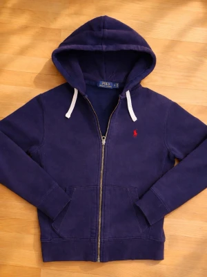 Mörkblå hoodie från Polo Ralph Lauren - Säljer nu min fina Ralph Lauren zip up original pris (2499kr) den är sparsamt använd och i fint skick. Den är dessutom riktigt vilket går att se på bild 4 då insidan av broderiet har minimalt vita trådar dessutom kan man se det på lapparna. Pris går att diskutera samt fråga mer bilder eller vid minsta fundering 😇