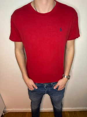 Röd t-shirt från Ralph Lauren - Klassisk röd t-shirt från Ralph Lauren med blå broderad logga på bröstet. T-shirten har rund halsringning och korta ärmar. Tillverkad i mjuk bomull för en skön känsla och enkel stil. Storlek M och super skick, endast 199kr. Hör av er vid frågor eller prisförslag💙 // studio II Resell 💯📦