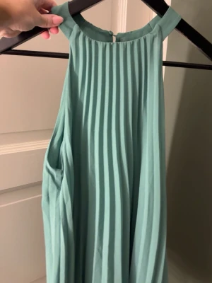 Ljusgrön plisserad ärmlös topp - Snygg ljusgrön ärmlös topp med plisserad design och hög hals. Toppen har en lös passform och knäpps i nacken. Perfekt för dig som gillar stilrena och trendiga plagg. Skriv för bild på🥰